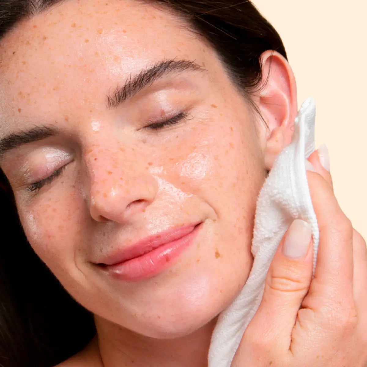 Woman applying a skincare product to her face with a towel.