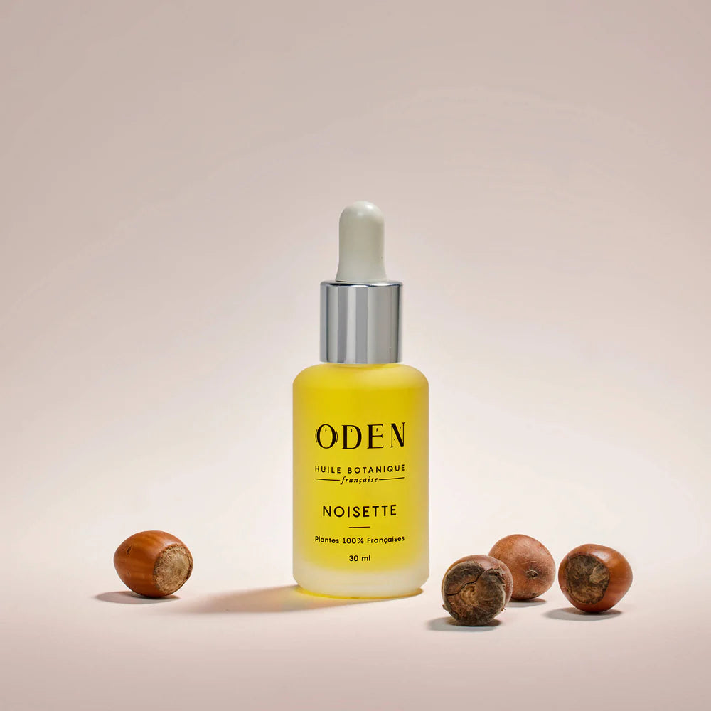 ODEN skincare dropper bottle with hazelnuts on a beige background