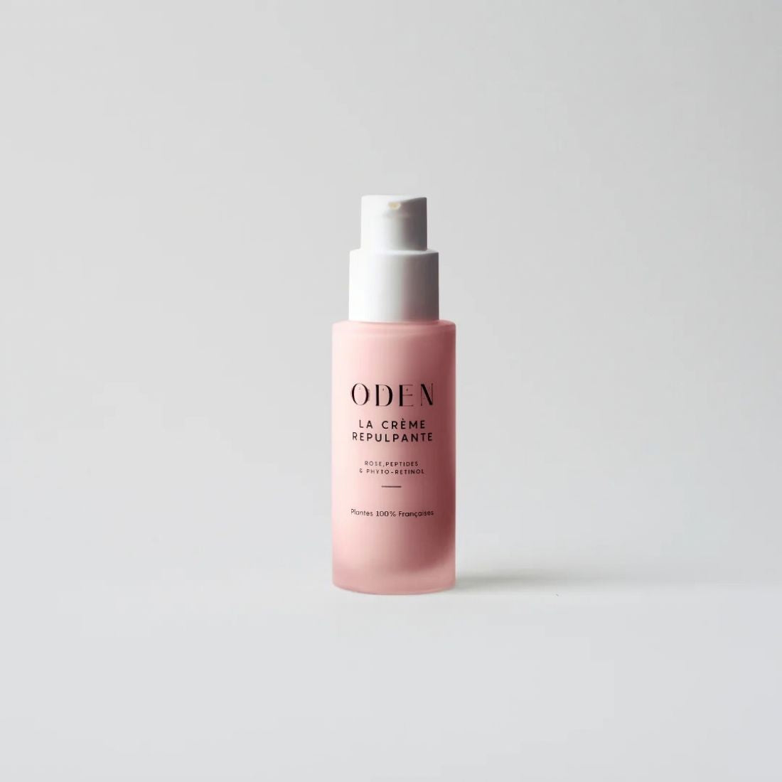 A pink cosmetic pump bottle with a white pump dispenser, featuring the brand name 'ODEN' and product name 'LA CRÊME REPULSANTE' printed on the front, set against a clean light gray background.