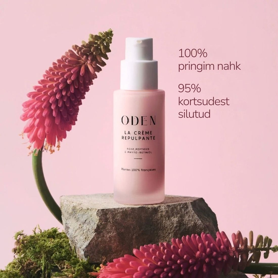 A bottle of ODEN La Crème Repulpante skin cream stands on a stone pedestal against a soft pink background, decorated with pink flowers and green moss. Text on the right reads '100% pringim nahk' and '95% kortsudet silutud'.
