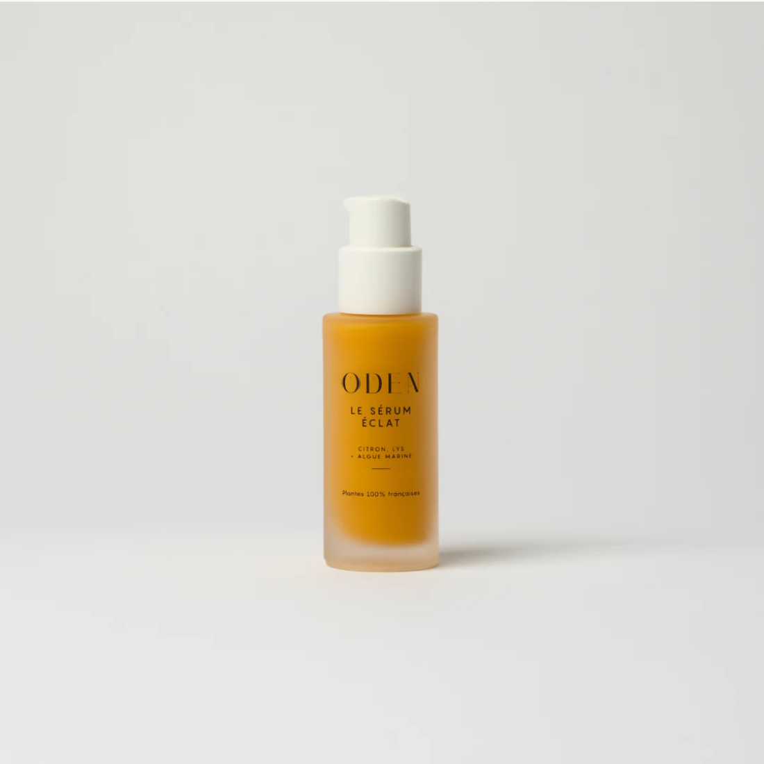 Radiance serum bottle with white cap and orange liquid on a light gray background