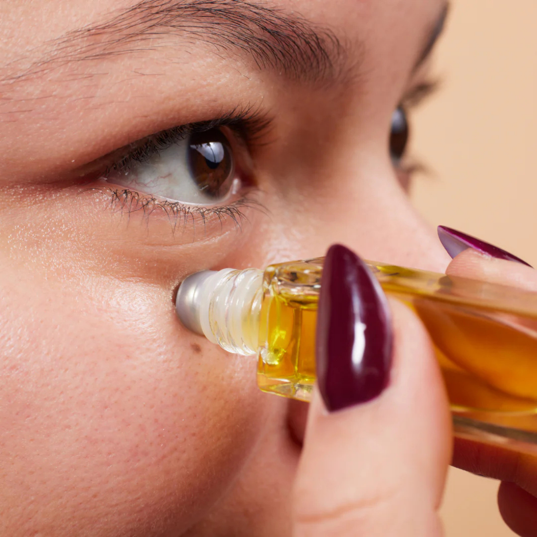 Close-up of a woman applying oil to her eye with a dropper.