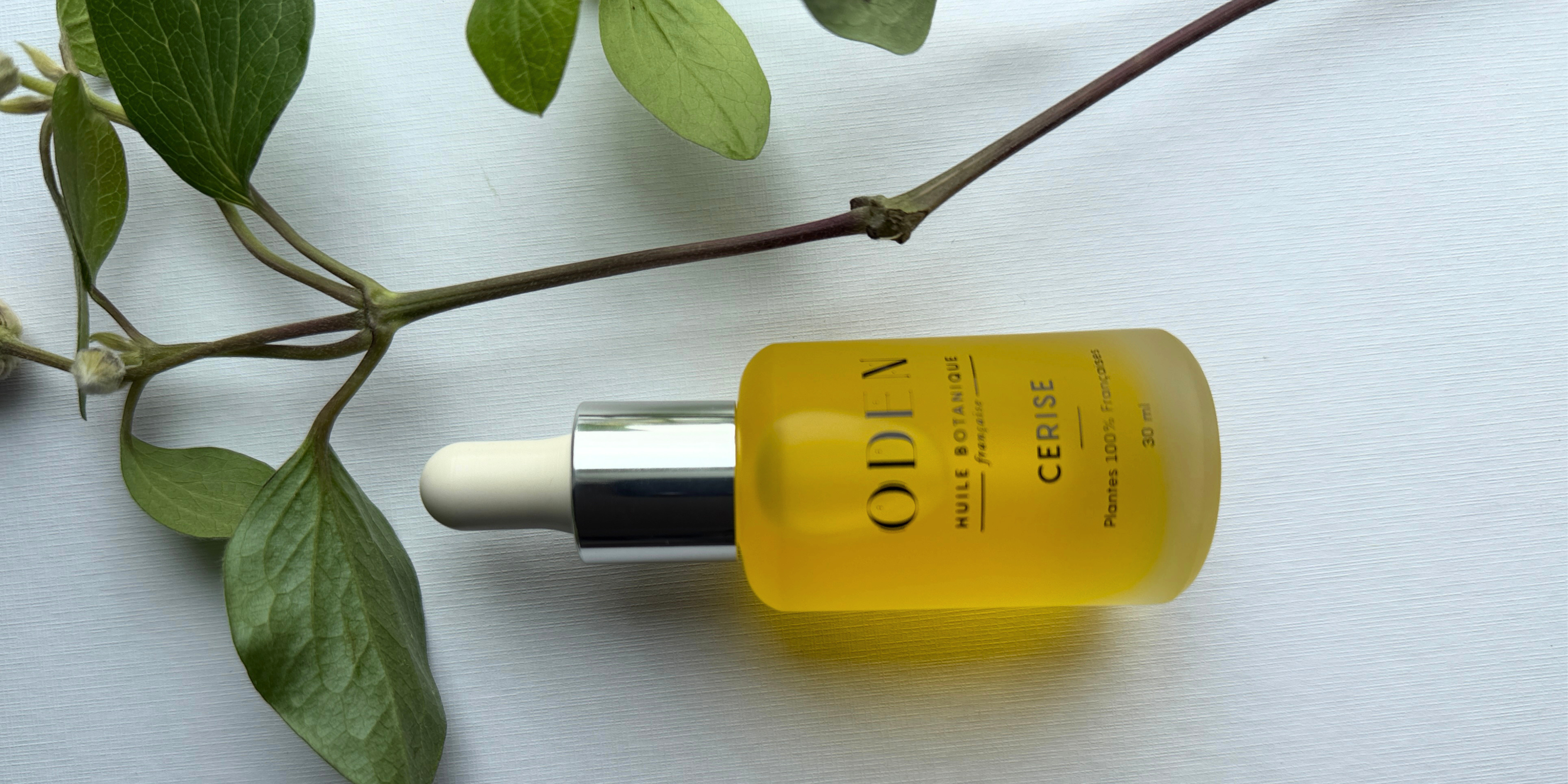Yellow bottle with dropper labeled 'ODEN' on a white surface with green leaves.